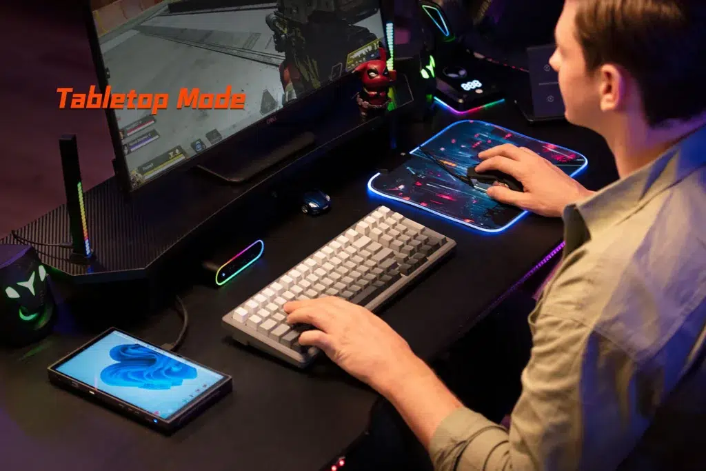 ONEXPLAYER X1 Mini 9 A user playing a first-person shooter on an external monitor connected to the ONEXPLAYER X1 Mini, showcasing its Tabletop Mode functionality for desktop-like gaming with a keyboard and mouse.